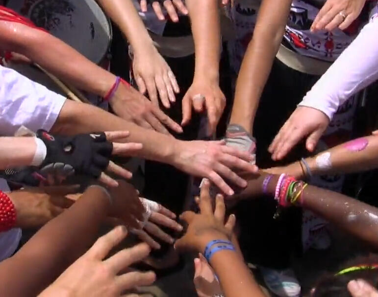 Still of hands coming together in a huddle from the documentary short &quot;Dance with Batala!&quot;